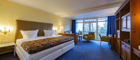 Een hotelkamer met een groot bed, nachtkastjes, een bureau, een stoel en een kledingkast.