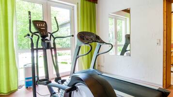 A home gym with an elliptical, a treadmill, and a mirror reflecting the room.