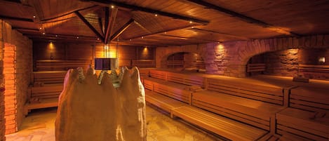 A stone-walled sauna with wooden benches and a central stone feature.