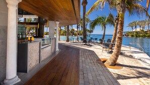 A covered outdoor area with a pool, palm trees, and a bar. - Lopesan Costa Meloneras Resort & Spa   (San Bartolomé de Tirajana)