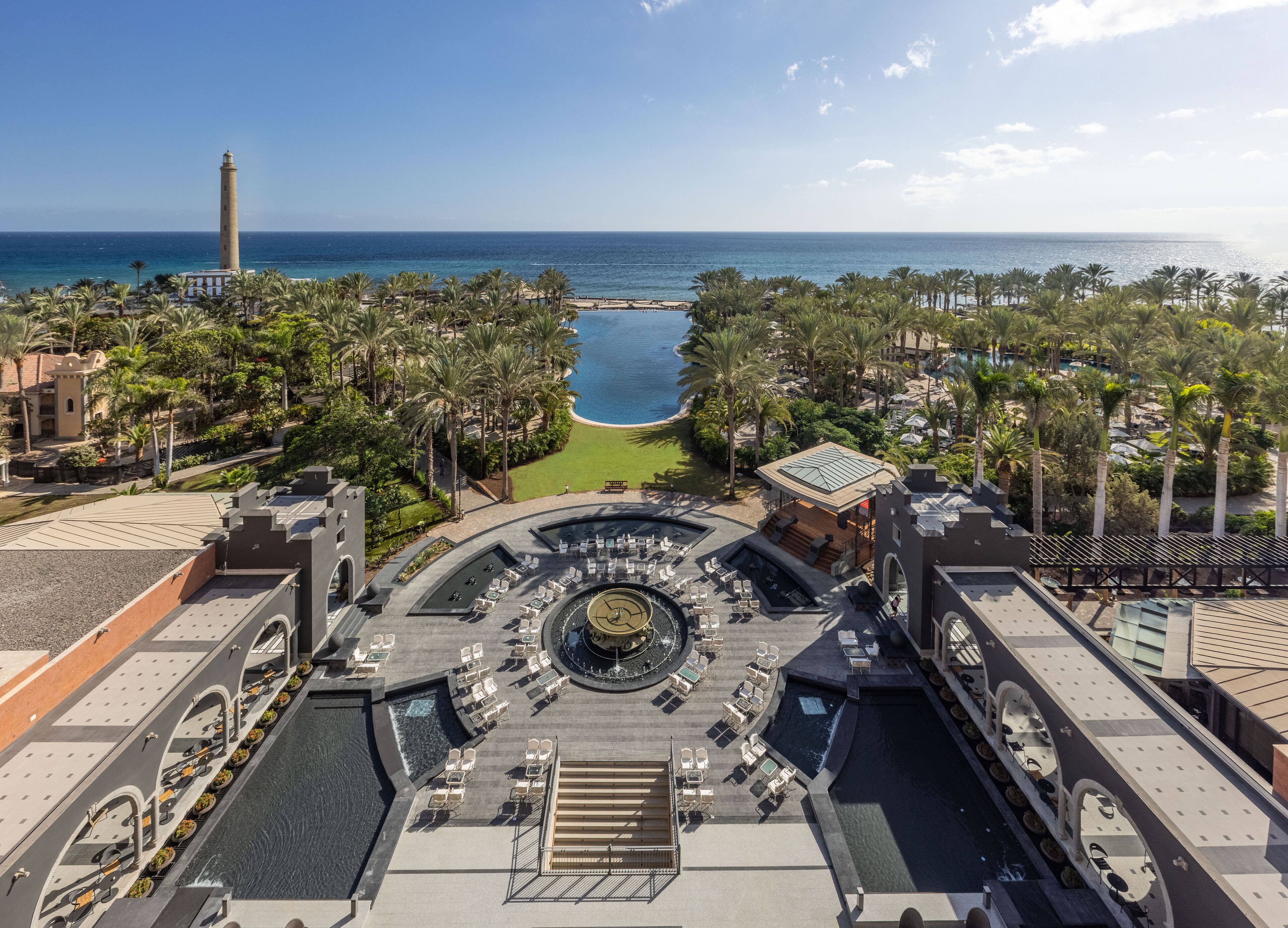 Een resort met een centraal gelegen zwembad, comfortabele zitgedeeltes en uitzicht op de oceaan.