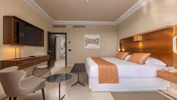 A modern hotel room with a large bed, a desk, a chair, a TV, and a small table.