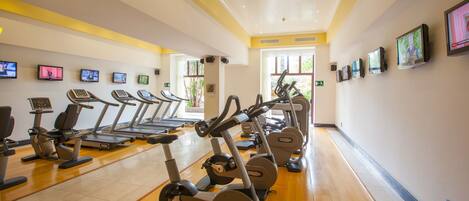 Un gimnasio con cintas de correr, bicicletas estáticas y equipo de ejercicio.