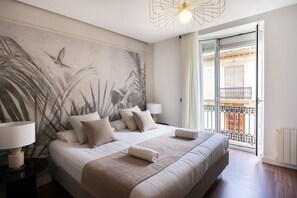 A hotel room with a large bed, two bedside tables, a wall mural, a balcony with a view, and a modern light fixture. - YOU & CO. J. Botánico Boutique Hotel (Valencia)