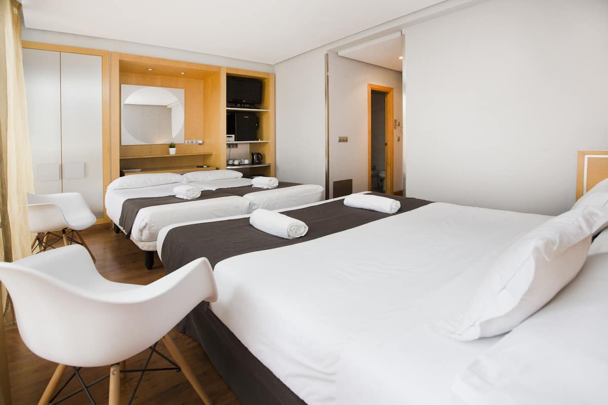 A hotel room with a large bed, a seating area with chairs, a television, and a wardrobe.