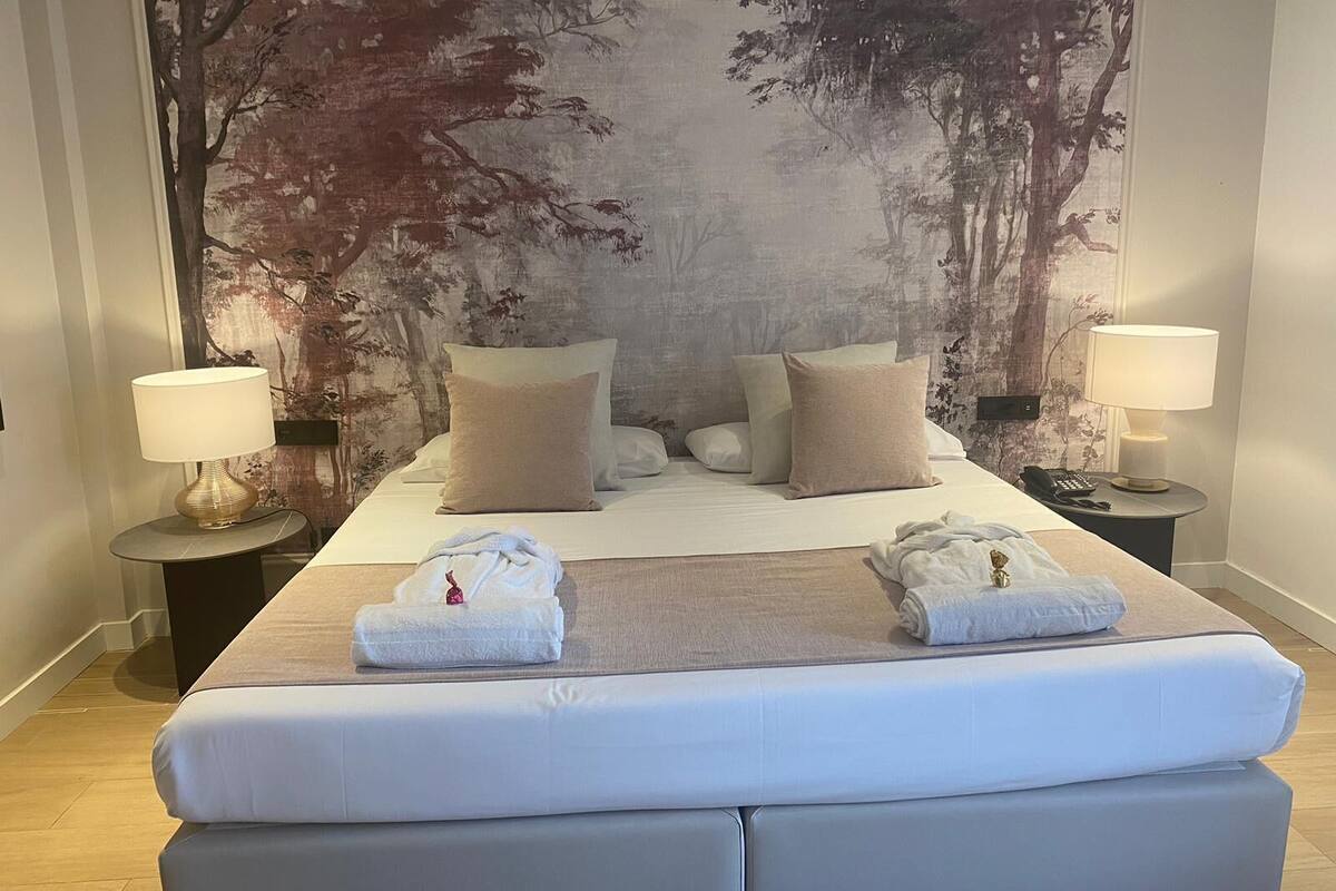 A hotel room with a large bed, two bedside tables, and a large painting on the wall.