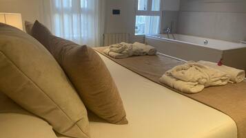 Una habitación de hotel con una cama, una ventana con cortinas, un radiador y una bañera.