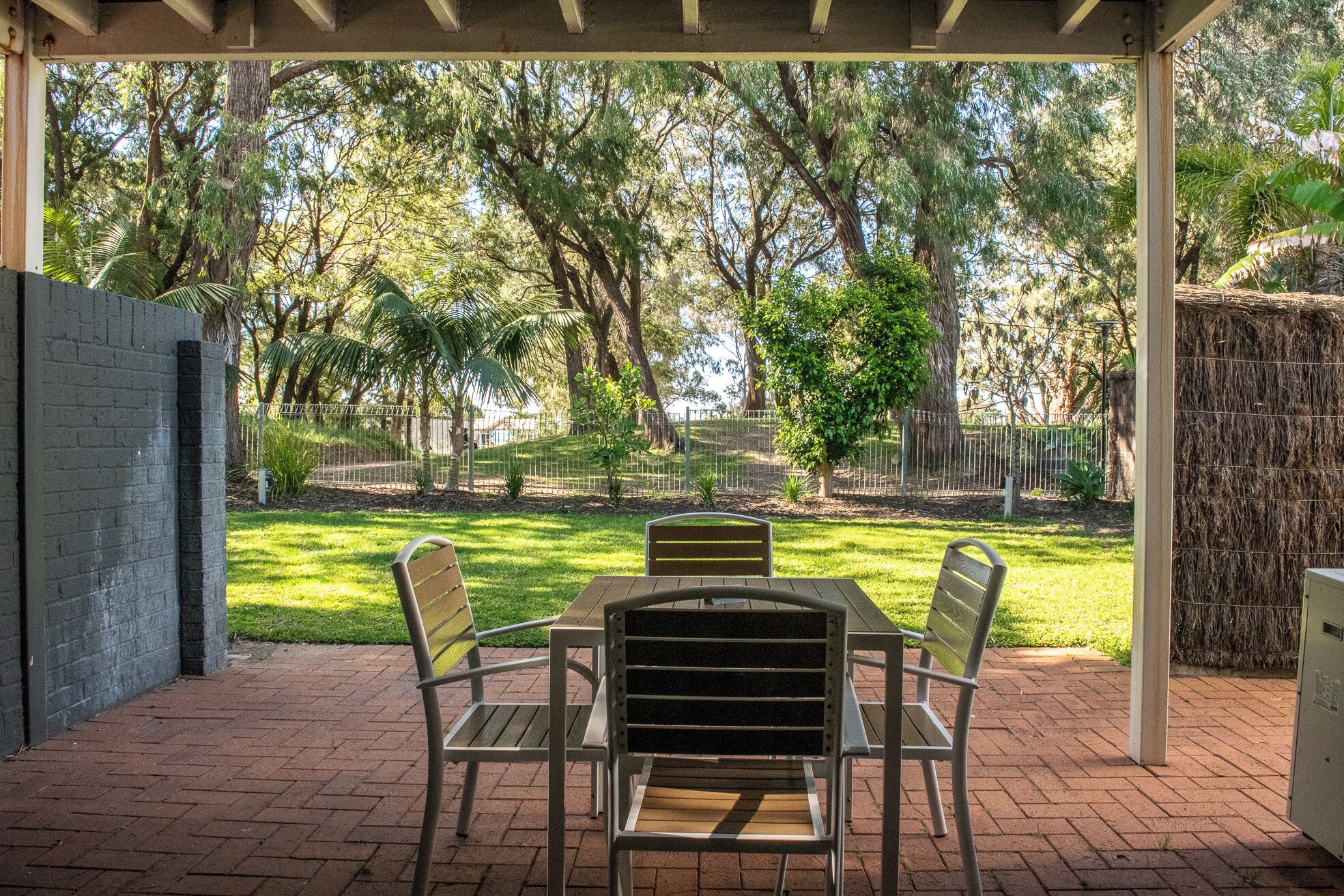 Une terrasse extérieure avec un sol en briques, une table et quatre chaises.