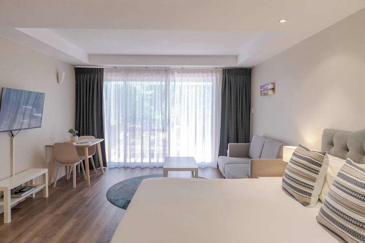 Una habitación de hotel con cama, escritorio, silla, televisor y sofá.