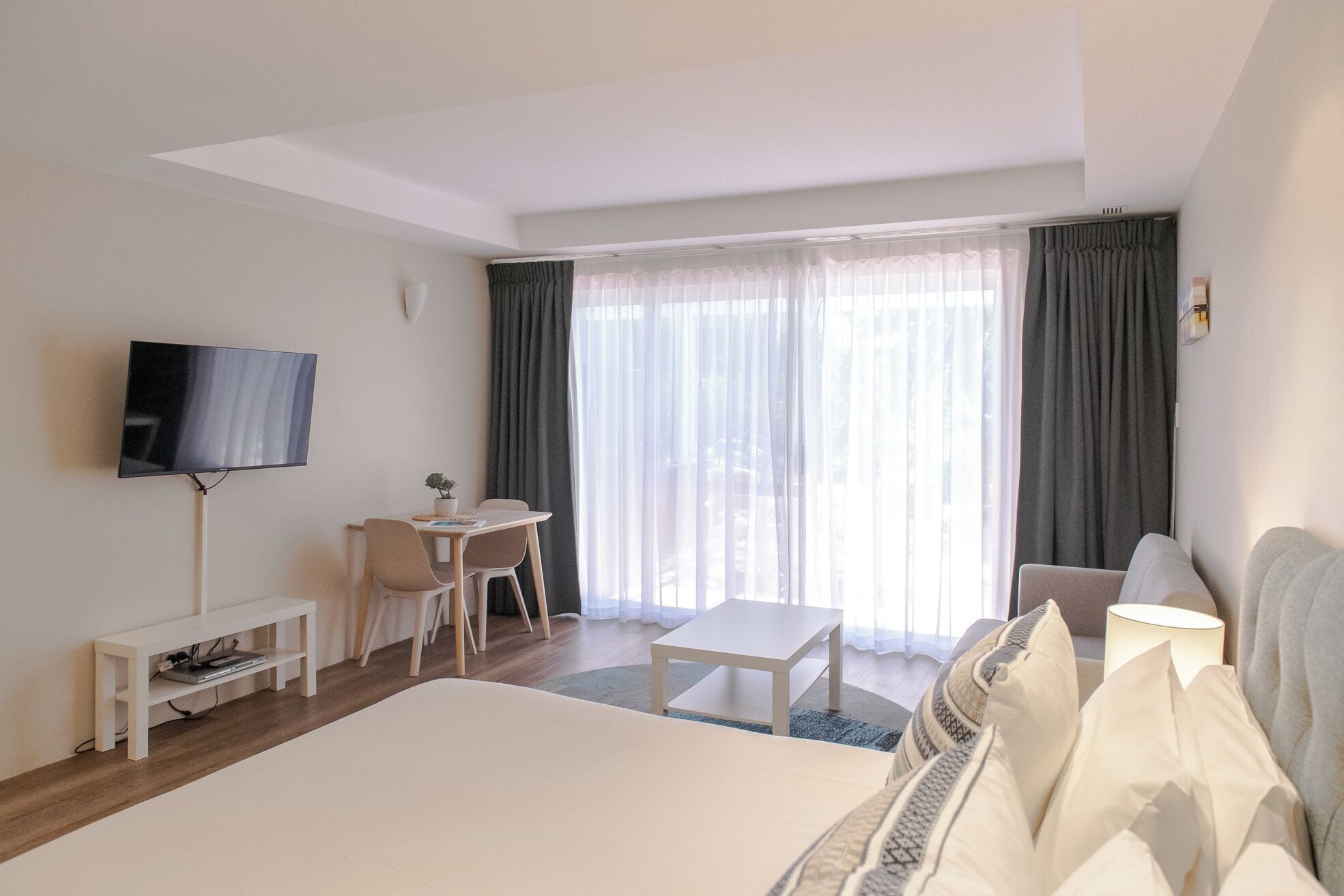 Une chambre d’hôtel avec un grand lit, un bureau avec deux chaises, une télévision et un canapé.
