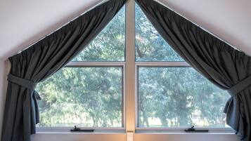 A bedroom with two beds, a ceiling fan, a window with curtains, and a bedside lamp.