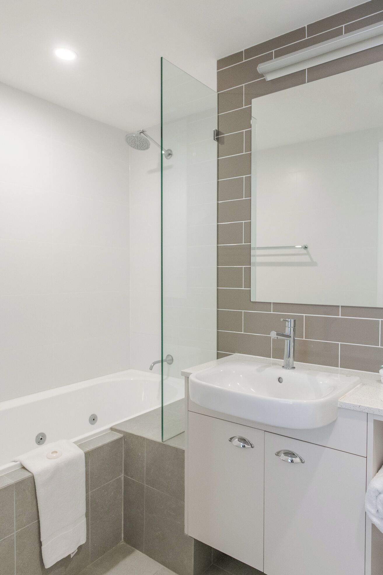 Een moderne badkamer met een douchecabine van glas, een vrijstaand bad en een wastafel met spiegel.
