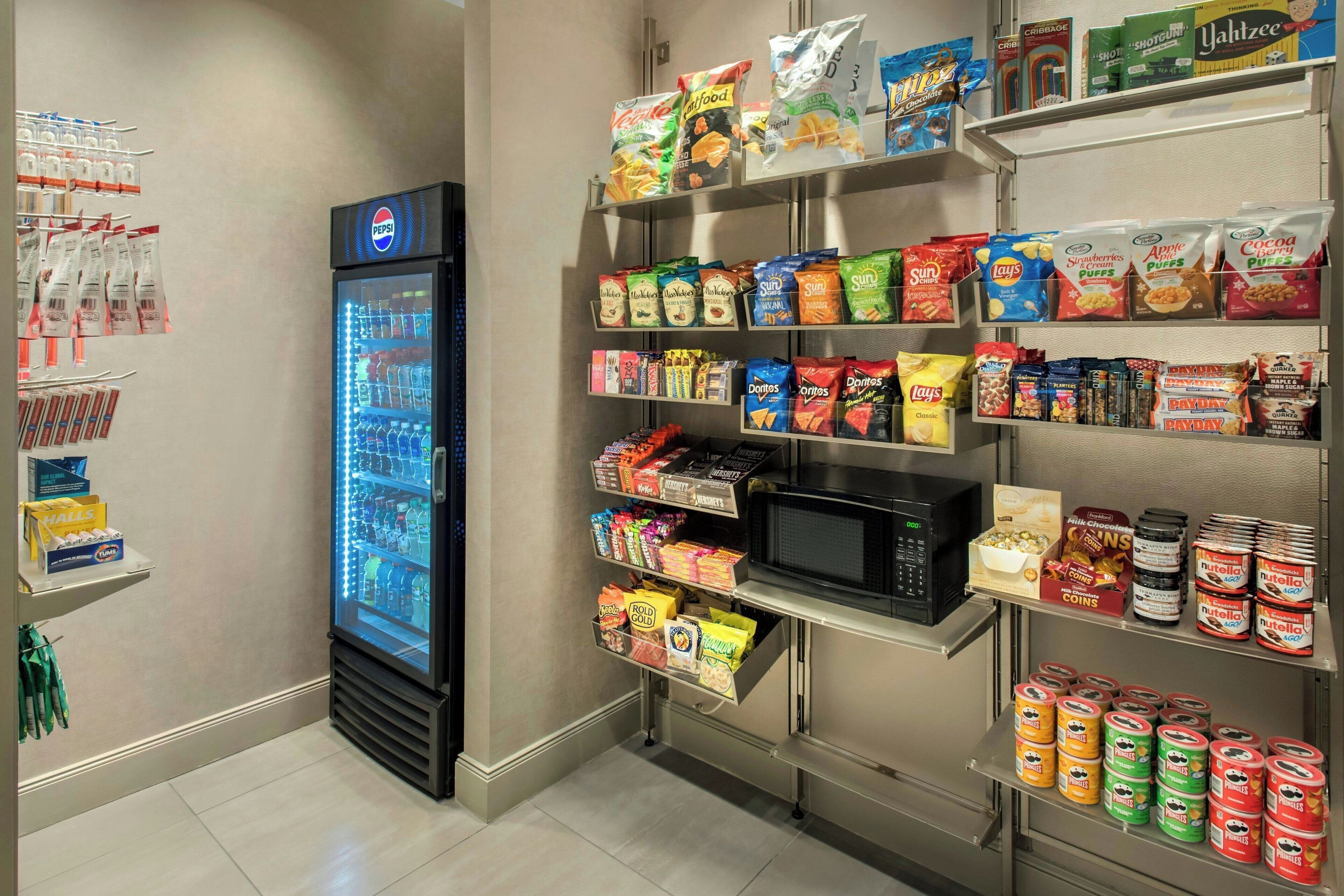 Un espace dédié aux collations et aux boissons, avec un réfrigérateur à boissons Pepsi, divers types de chips et des conserves.