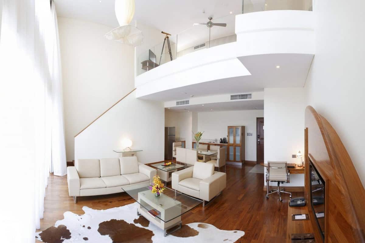 A spacious living area with a high ceiling, a glass coffee table, a sofa, and a cowhide rug.