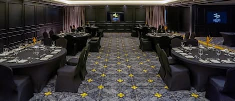 A conference room with round tables, black chairs, and a patterned carpet.
