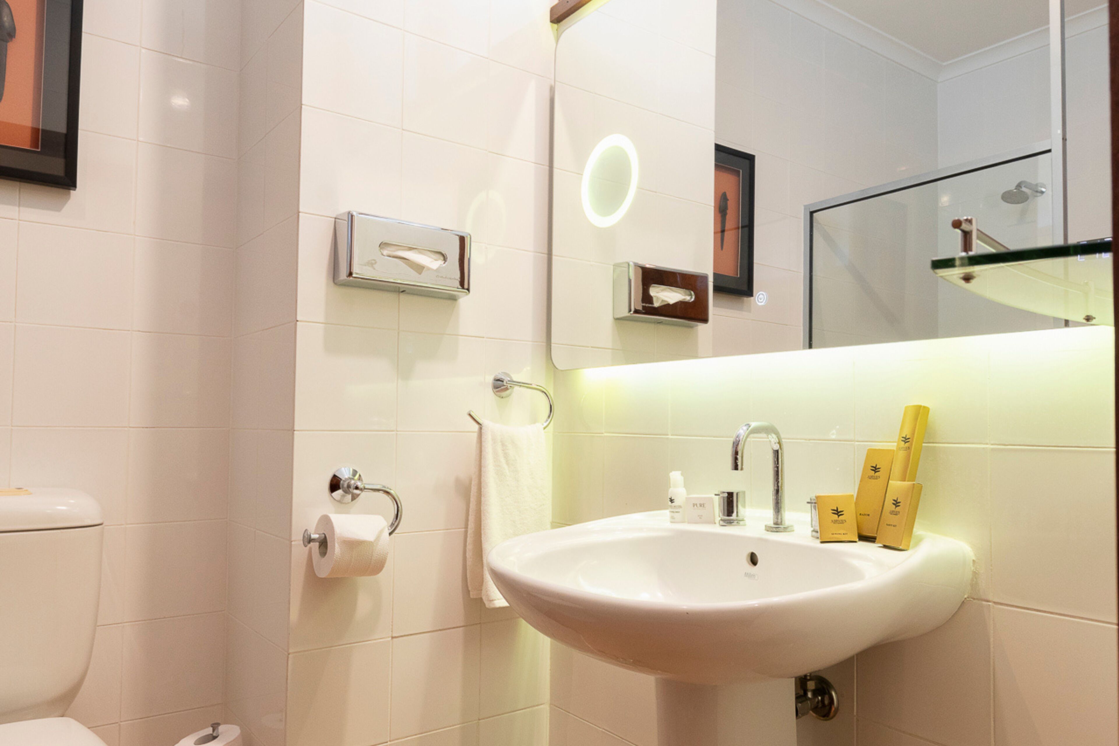 Ein modernes Badezimmer mit Waschbecken, Toilette und Spiegel in Weiß.