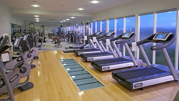 A gym with multiple treadmills, exercise machines, and a wooden floor.