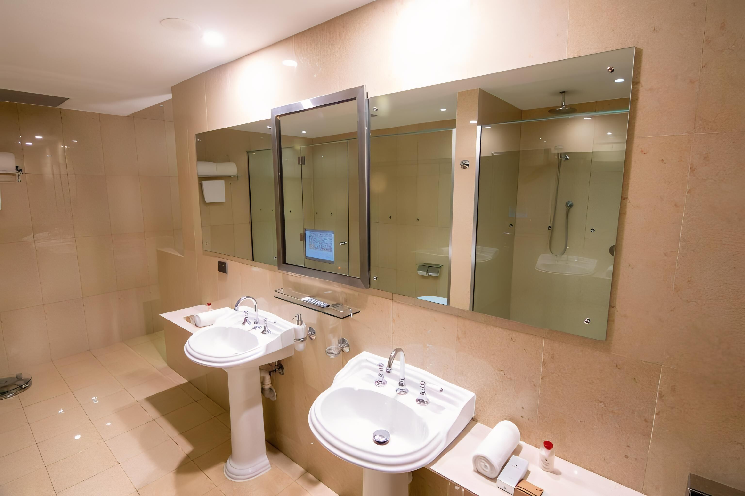 Un baño moderno con dos lavamanos, un espejo grande y una ducha con mampara de vidrio.