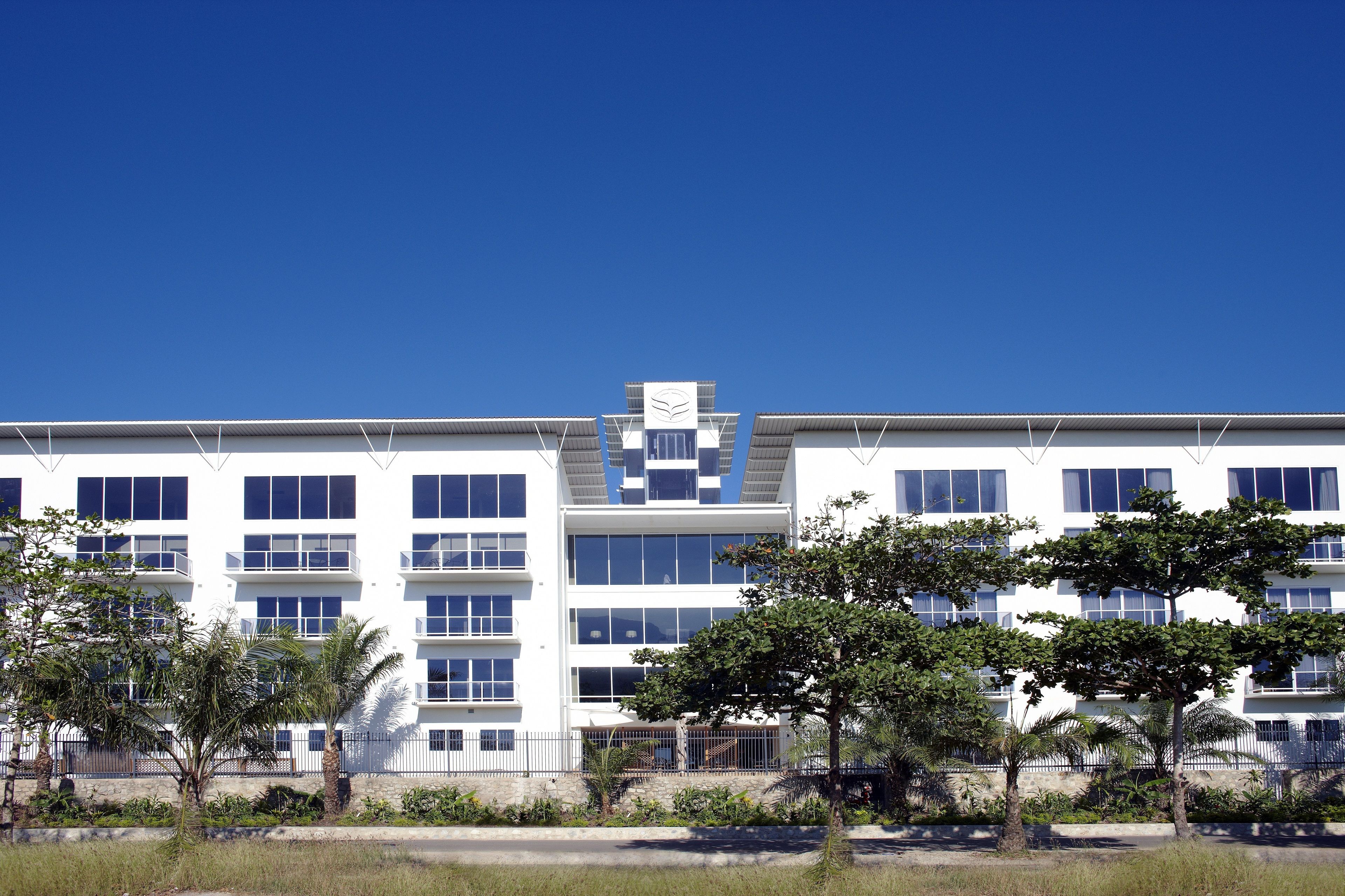Un immeuble moderne à plusieurs étages, doté d’une façade symétrique, de grandes fenêtres et d’une entrée centrale.