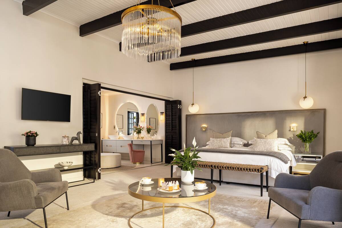 A modern bedroom with a large bed, bedside tables, a round coffee table, and a TV mounted on the wall.