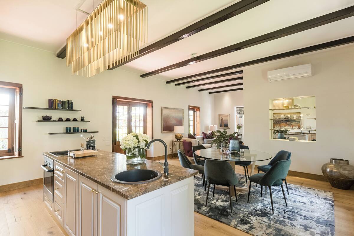 A modern kitchen with a central island, built-in appliances, and a dining area with a glass table and chairs.