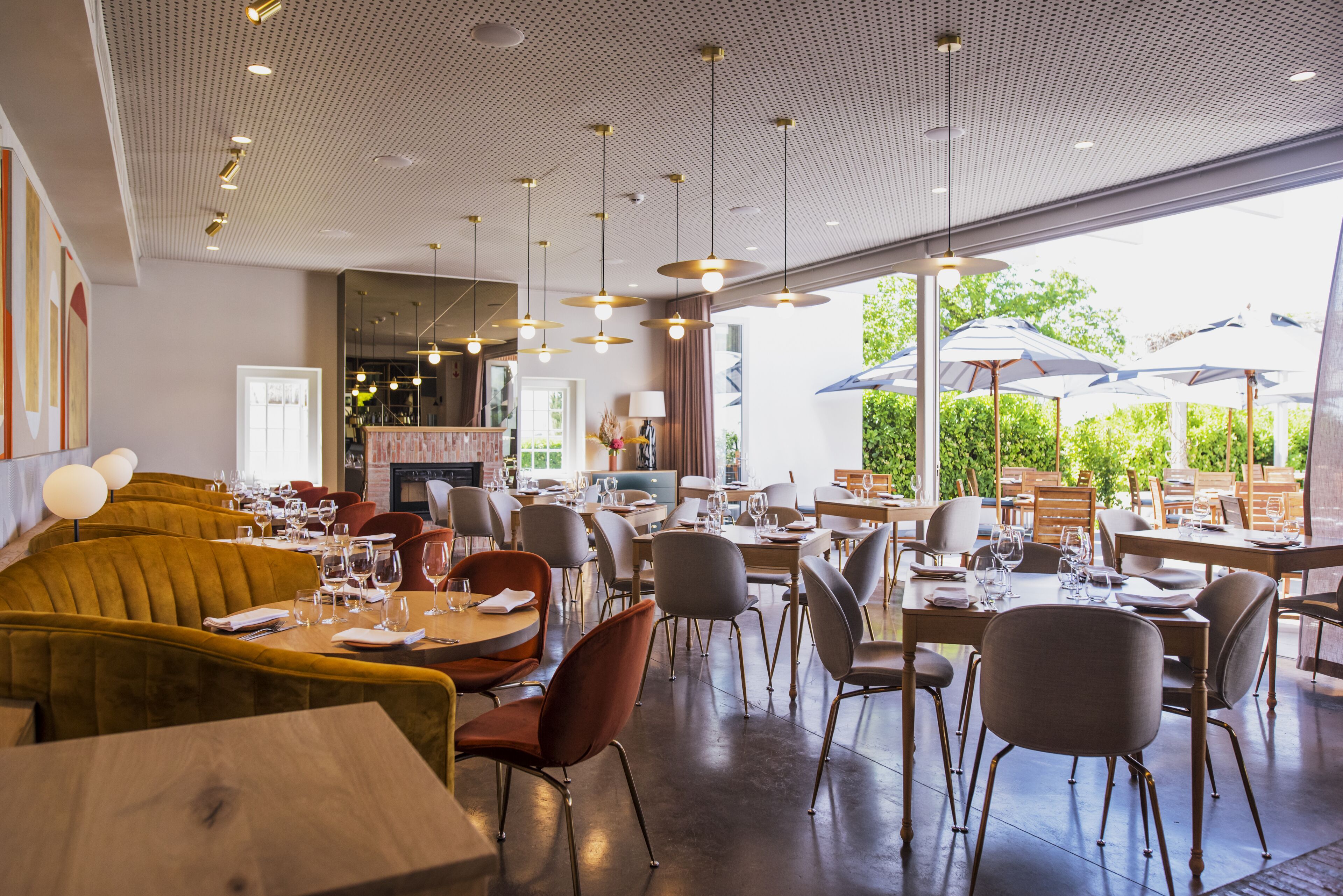 Un ristorante dall'arredamento moderno, con diverse opzioni di posti a sedere tra cui tavoli e banconi, e vista sull'esterno grazie a grandi finestre.