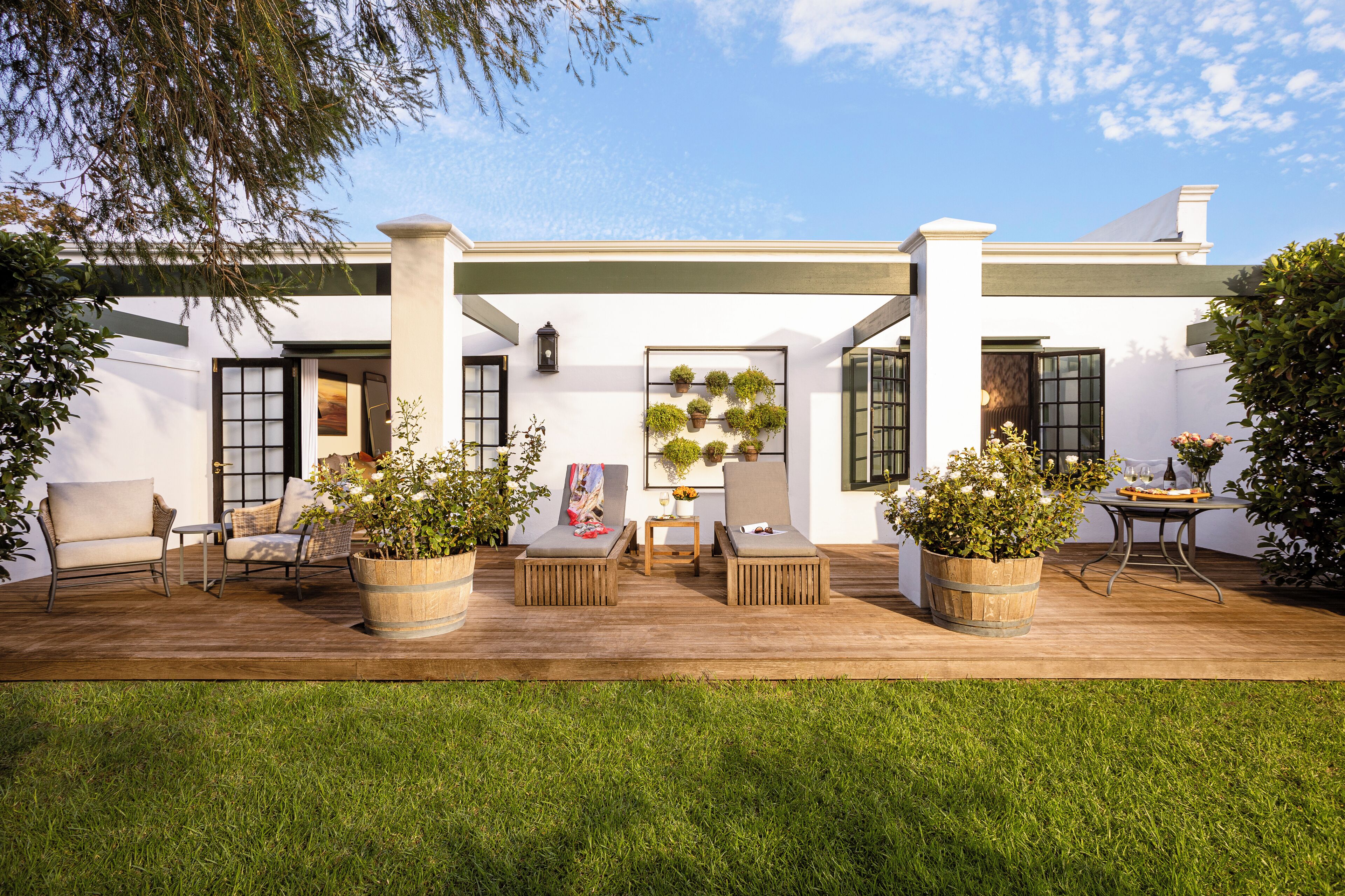 A patio with two cushioned chairs, a small table, and potted plants.