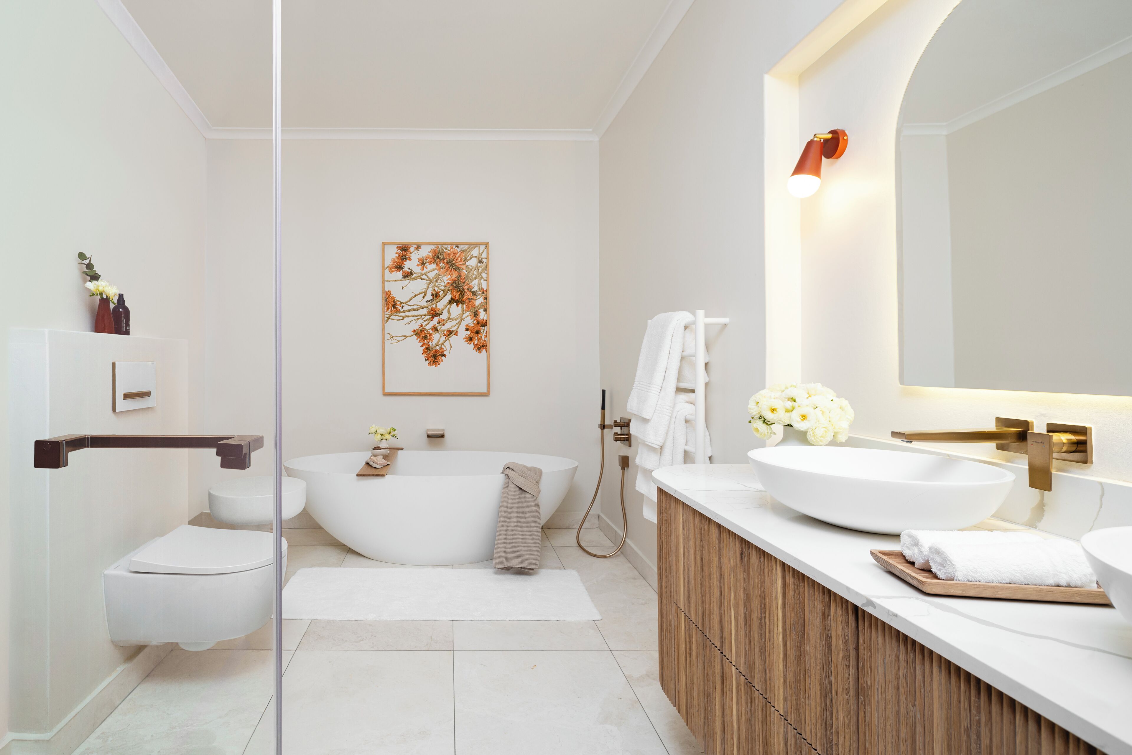 A modern bathroom with a freestanding bathtub, a large mirror, and a wooden vanity.