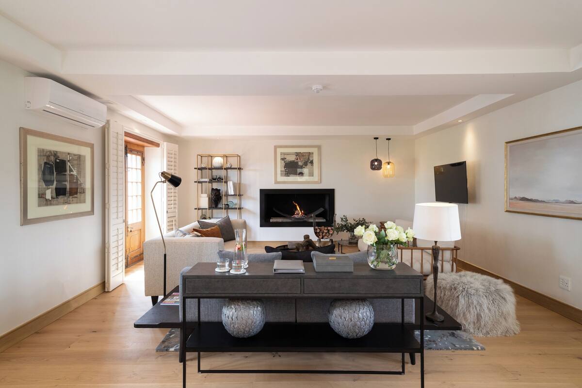 A modern living room with a fireplace, a flat-screen TV, and a dining area with a table and chairs.