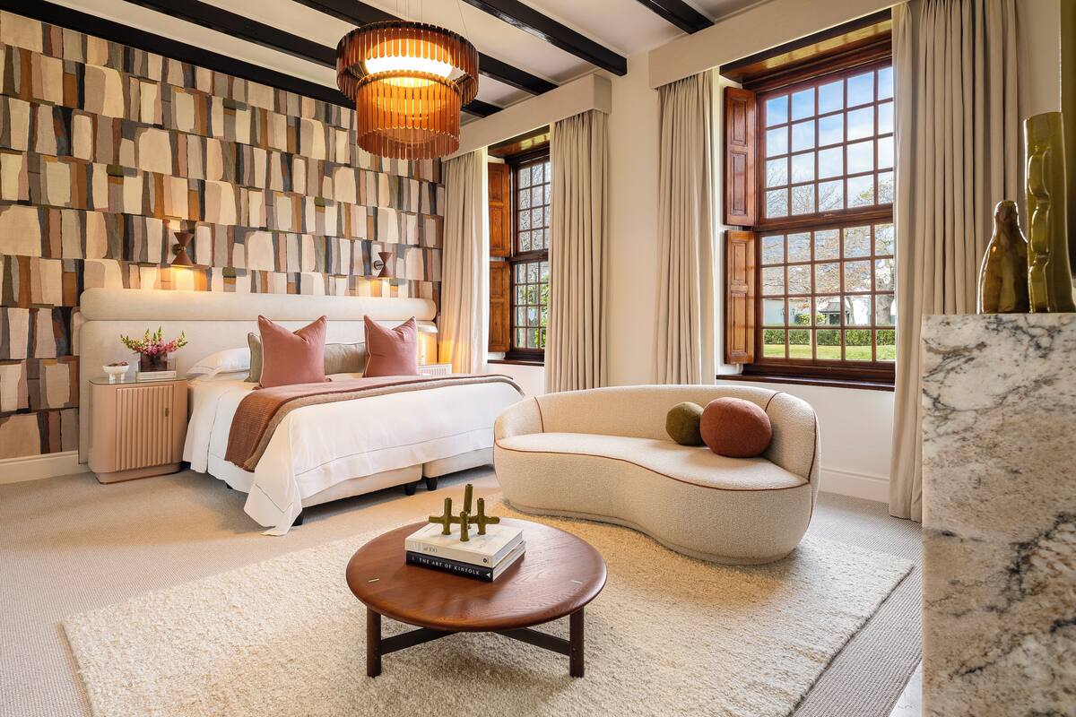 A bedroom with a bed, bedside tables, a sofa, a coffee table, and a view of the outdoors.