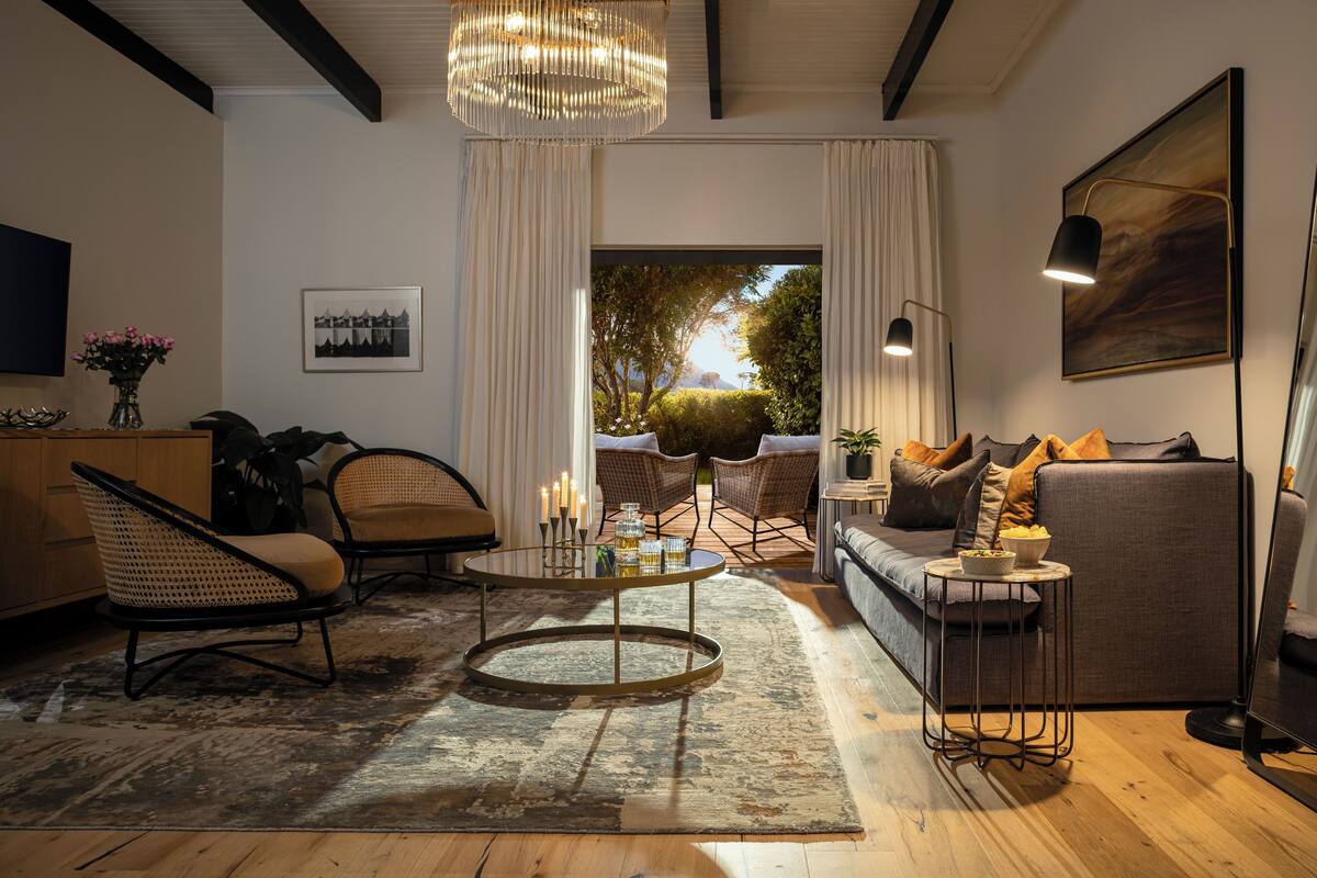 A modern living room with a sofa, chairs, a coffee table, and a large window with a view of greenery.