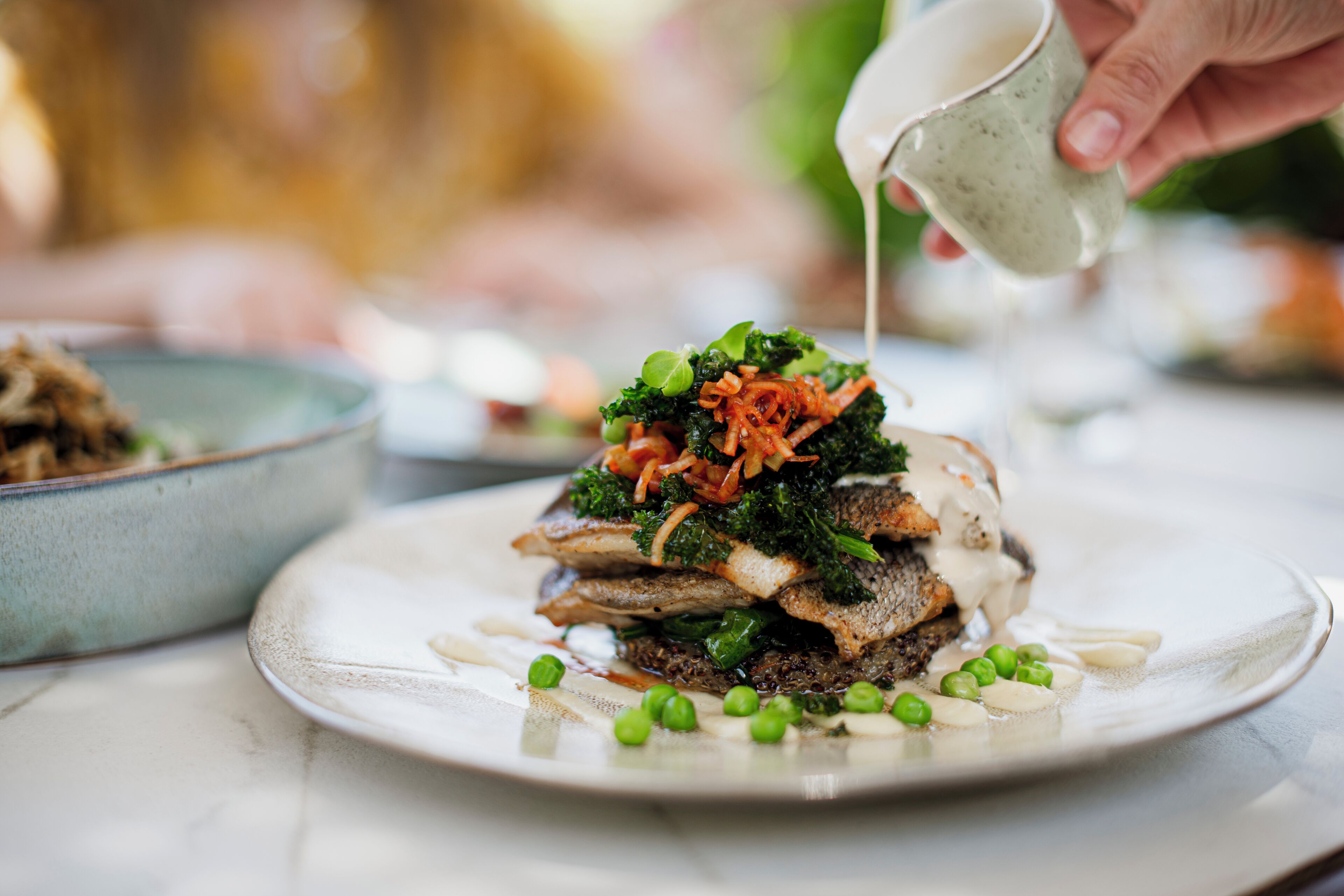 Ein Teller Essen mit verschiedenen Belägen und Soße, die darüber gegossen wird.