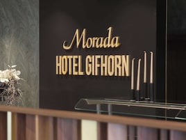 Un letrero de hotel con el nombre 'Morada Hotel Gihorn' en letras doradas sobre un fondo negro.