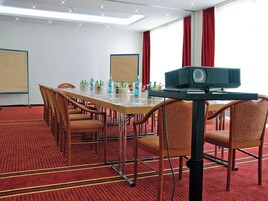 A conference room with a long table, chairs, a projector, and a screen.
