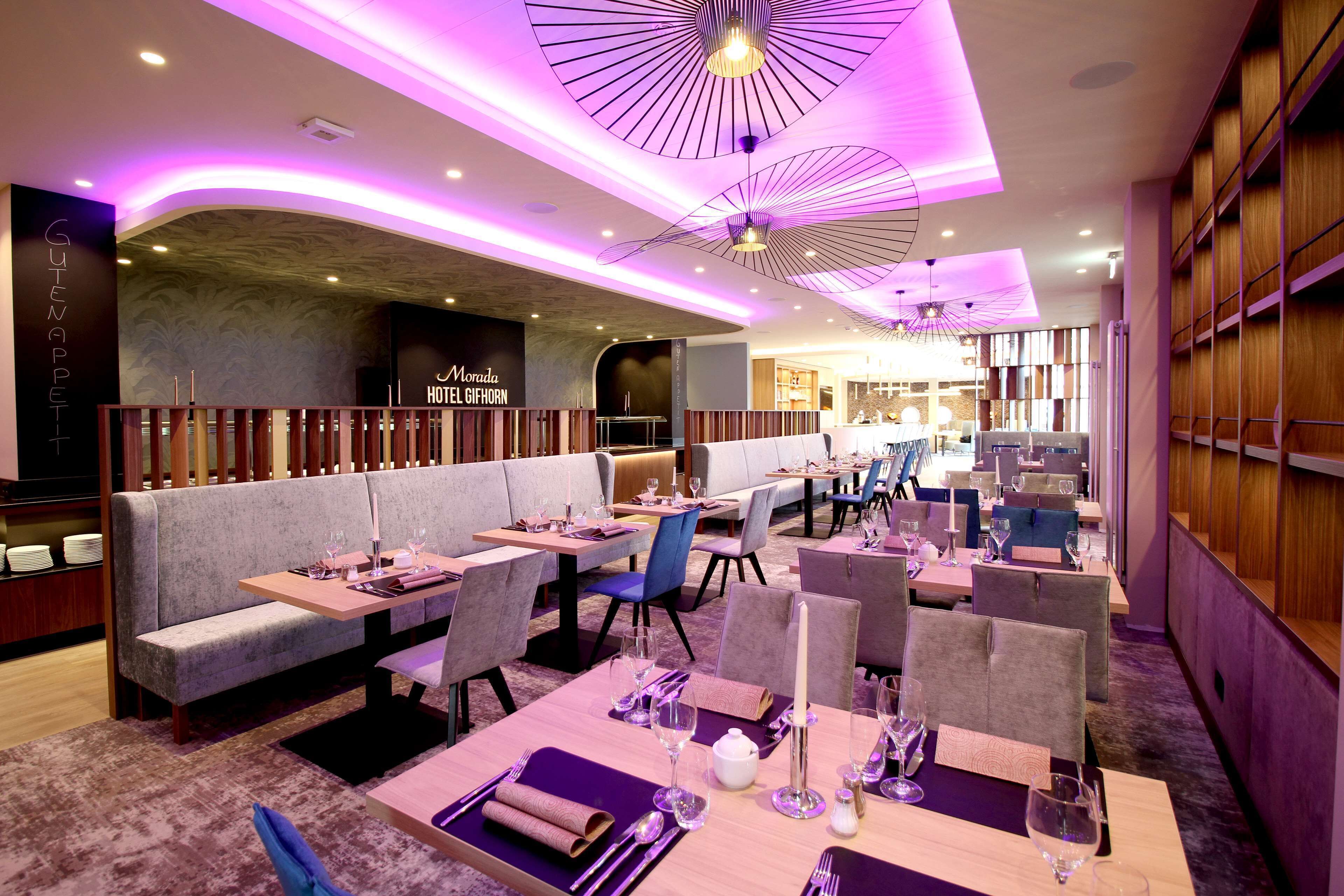 A modern restaurant with a cozy seating area, including booths and tables, and a bar in the background.