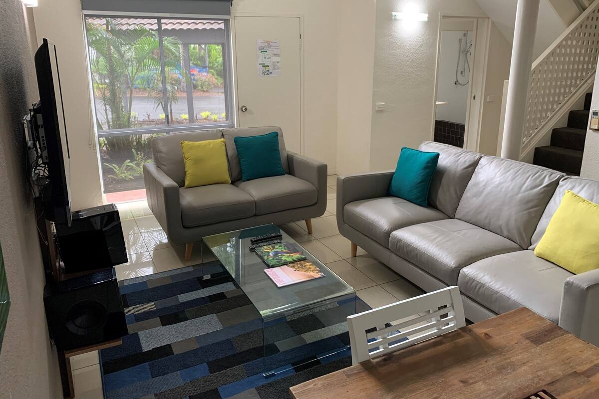 A modern living room with two grey sofas, a glass coffee table, and a patterned rug.