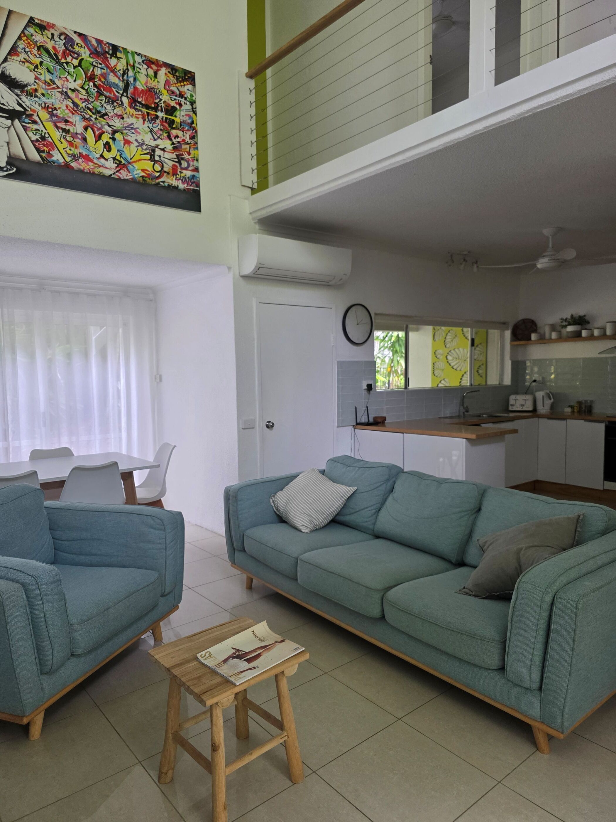 Een woonkamer met een bank, een klein houten tafeltje en een eethoek met stoelen.