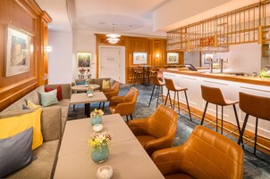 Un vestíbulo de hotel con zona de comedor, bar y mostrador de recepción.
