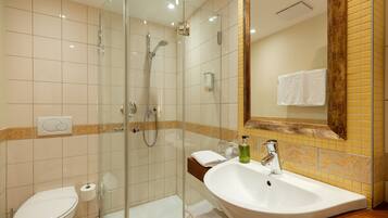 Une salle de bain avec une douche à parois de verre, un lavabo blanc et des toilettes.