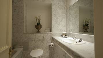 A bathroom with a marble sink, toilet, and a mirror.