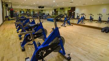A gym with multiple exercise bikes and a wooden floor.