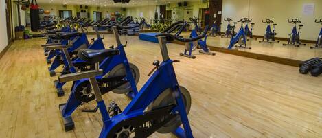 A gym with multiple exercise bikes and a wooden floor.