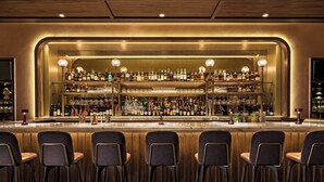 A bar area with multiple shelves of bottles and glasses, bar stools, and a warm, well-lit ambiance.