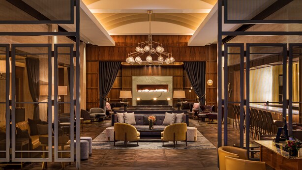 A spacious lobby with a central seating area, a large chandelier, and a fireplace.