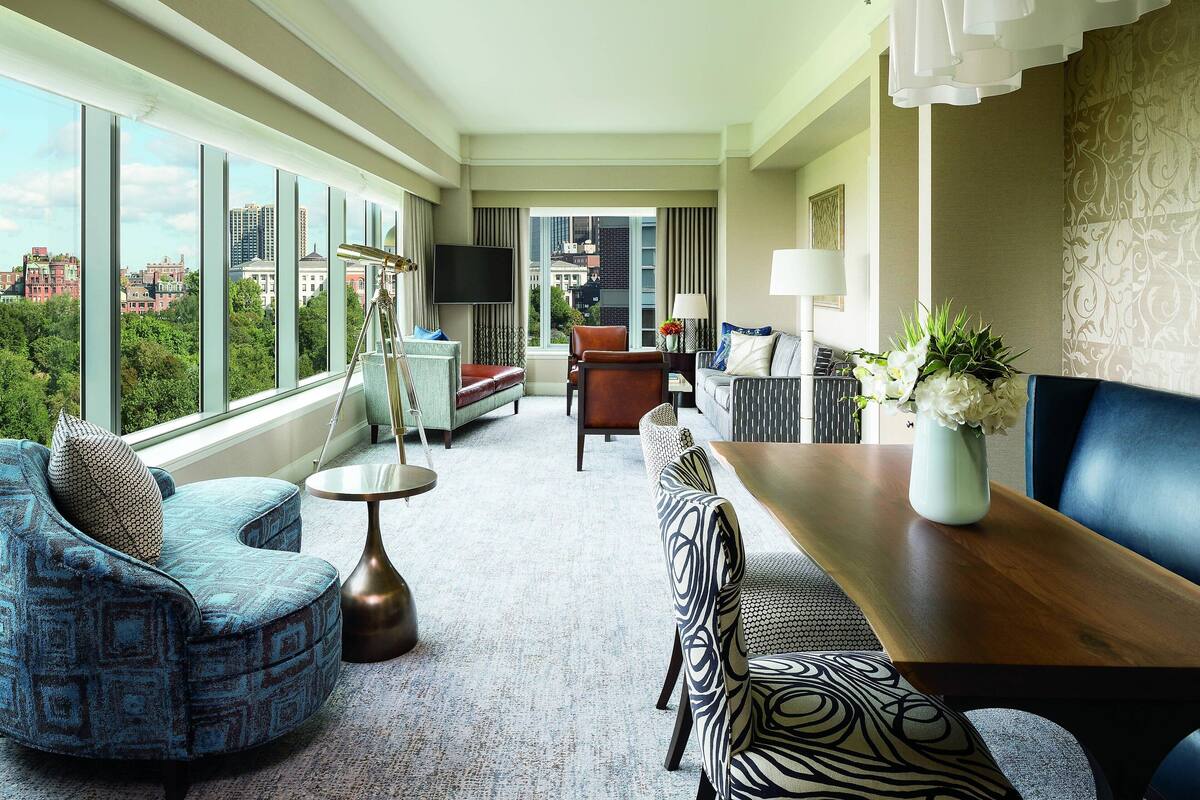 Une chambre d’hôtel moderne dotée d’une grande fenêtre, d’un canapé, d’une table à manger et d’un téléviseur.