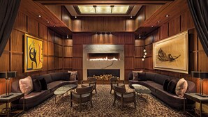 A luxurious living room with a fireplace, leather sofas, and a patterned carpet.
