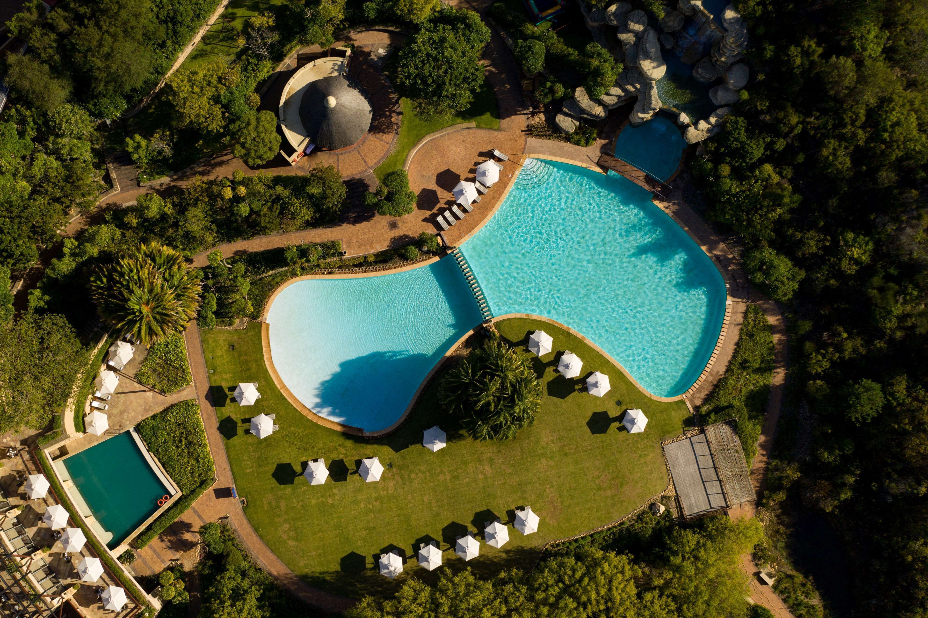 An aerial view of a resort with a large swimming pool, lounge areas, and a gazebo.