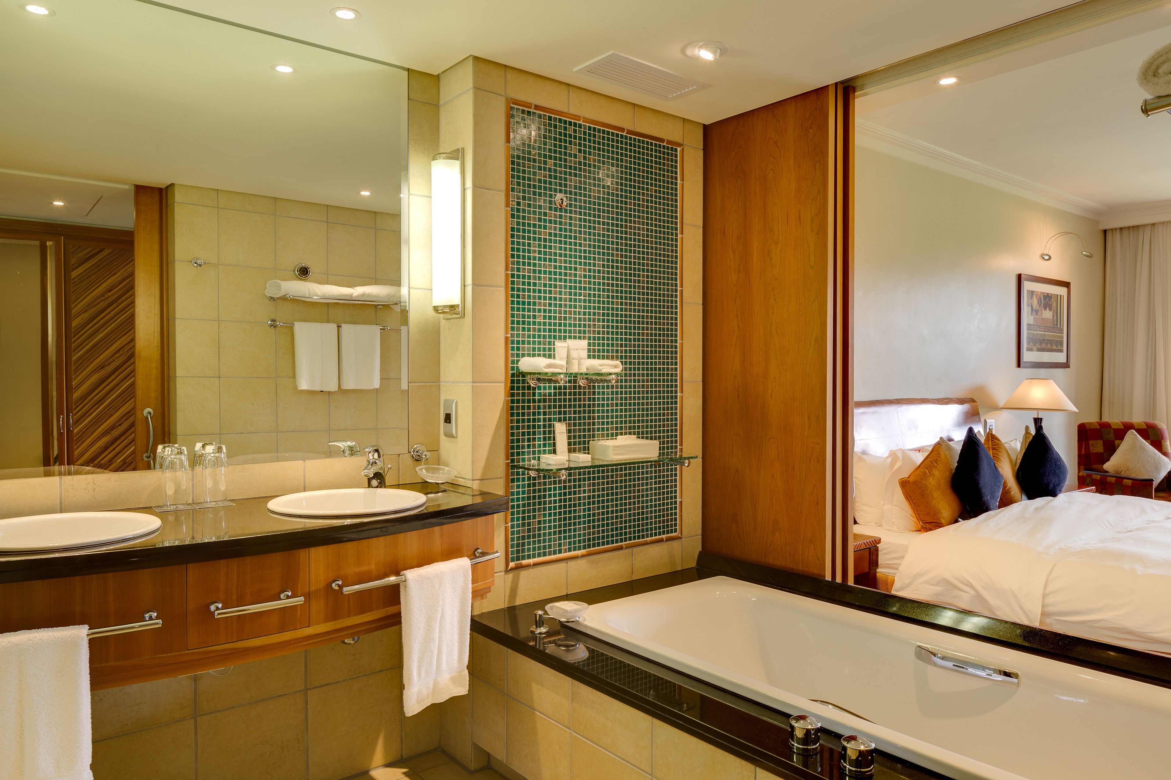Ein Hotelbad mit zwei Waschbecken, einem großen Spiegel, einer Badewanne und einer Duschkabine.