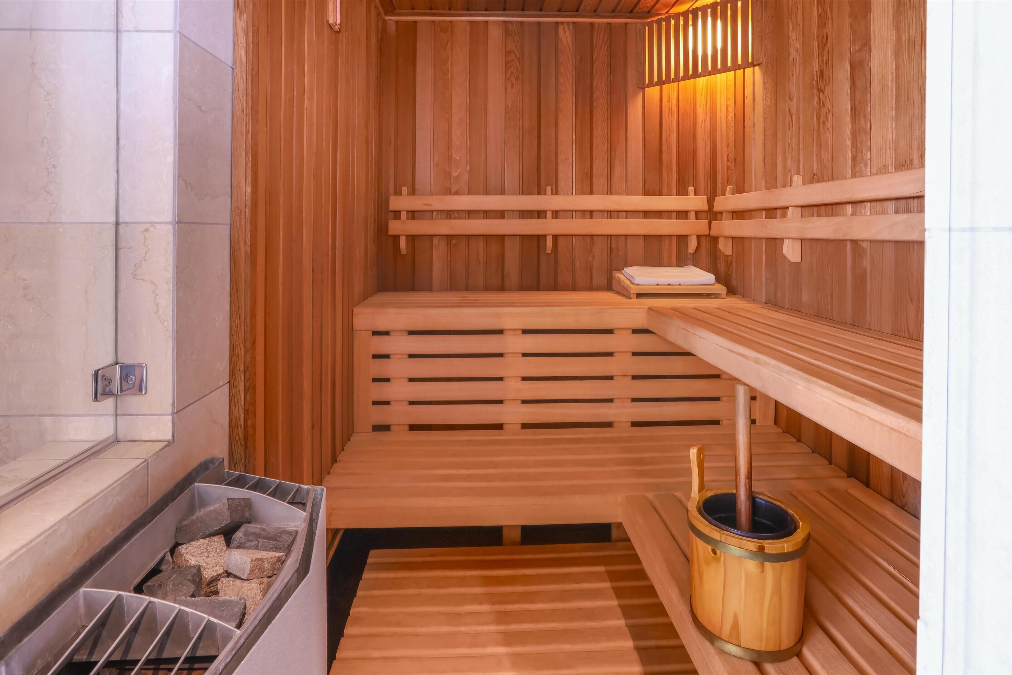 A sauna with wooden benches, a stone basin, and a wooden bucket.