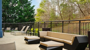 An outdoor patio area with a sectional sofa, lounge chairs, and a round table.